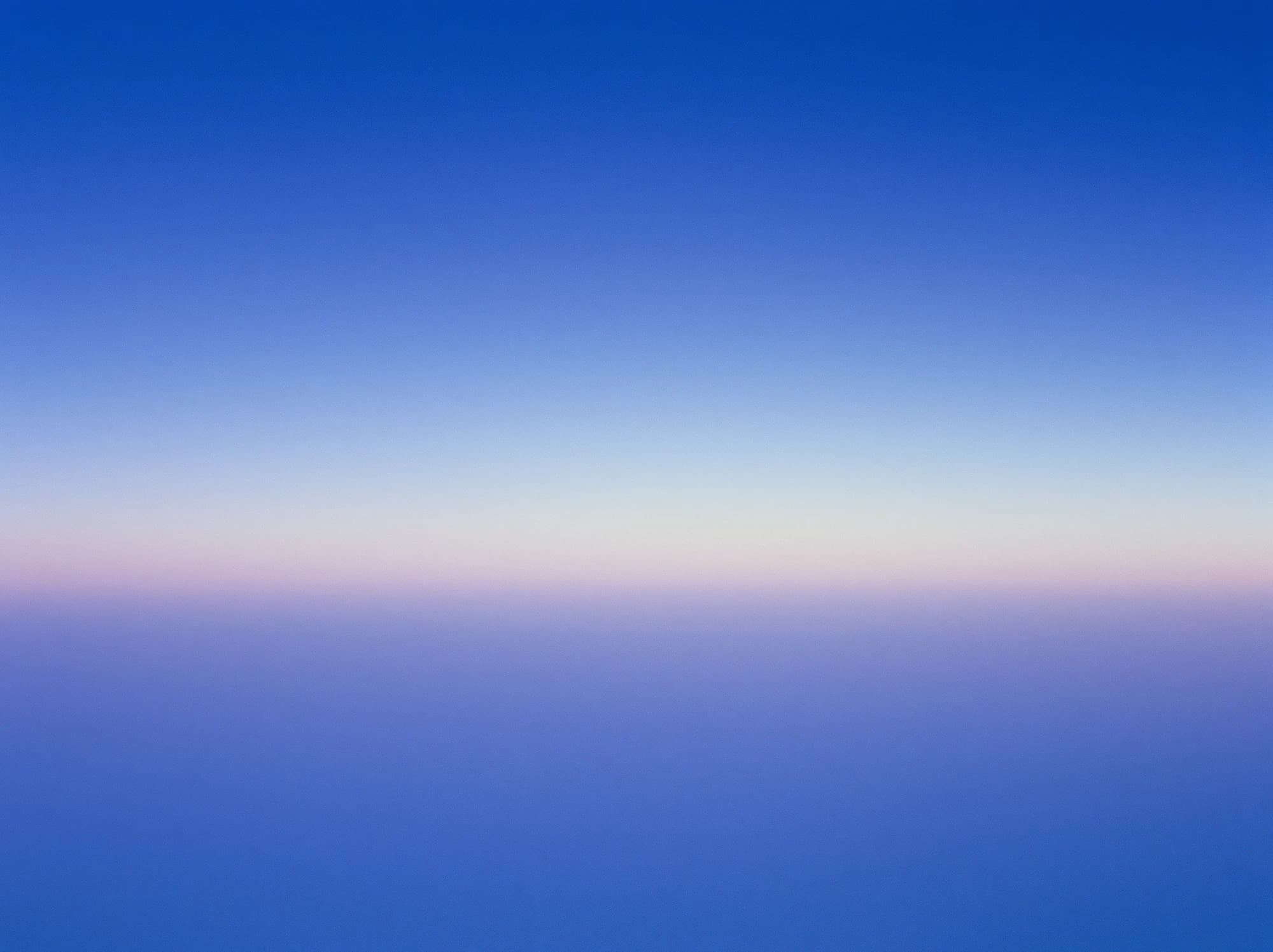 Ein gleichmäßiger blauer Farbverlauf mit einem schmalen blassrosa Lichtstreifen am Horizont.